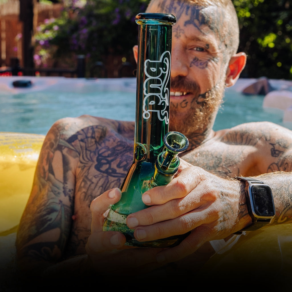 Man sitting in pool with a teal Bud Beaker Bong 