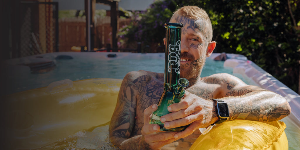 Man sitting in pool with a teal Bud Beaker Bong 
