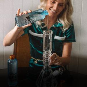 Woman pouring Piece Water Solution into her glass beaker bong